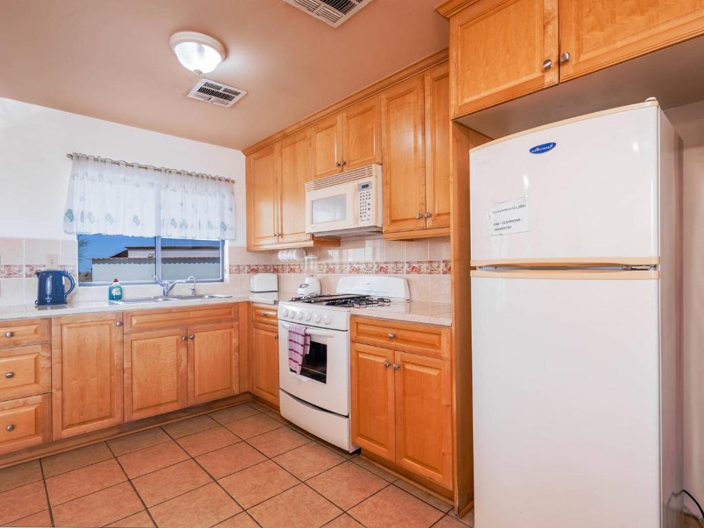 a kitchen with a white refrigerator and wooden cabinets at Casa Tilly El Dorado Ranch San Felipe Rental Home in Playa El Paraíso