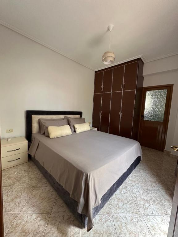 a bedroom with a large bed with a wooden cabinet at Saranda Seaside & Port Rooms-3 min from Port! in Sarandë