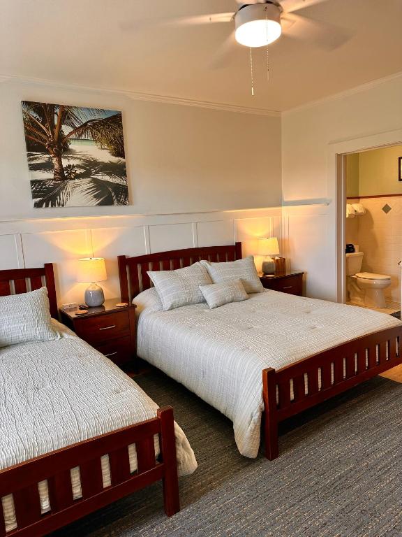 a bedroom with two beds and two lamps and a mirror at Hilo Town Inn in Hilo