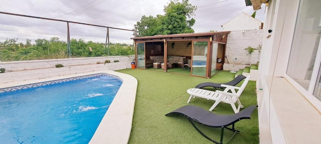 un patio trasero con piscina, sillas y una casa en Poni Pisador, en Mairena del Aljarafe