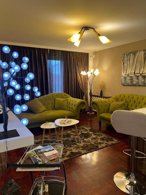 a living room with green couches and blue accents at Mona Lux apartman in Arandelovac
