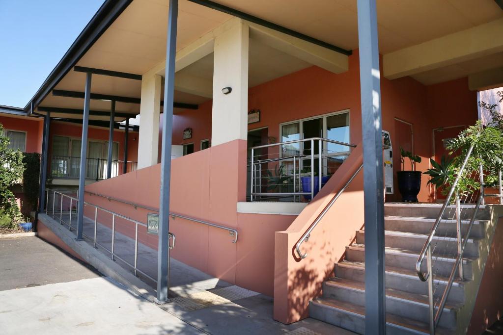 a pink building with stairs in front of it at Forbes Victoria Inn in Forbes