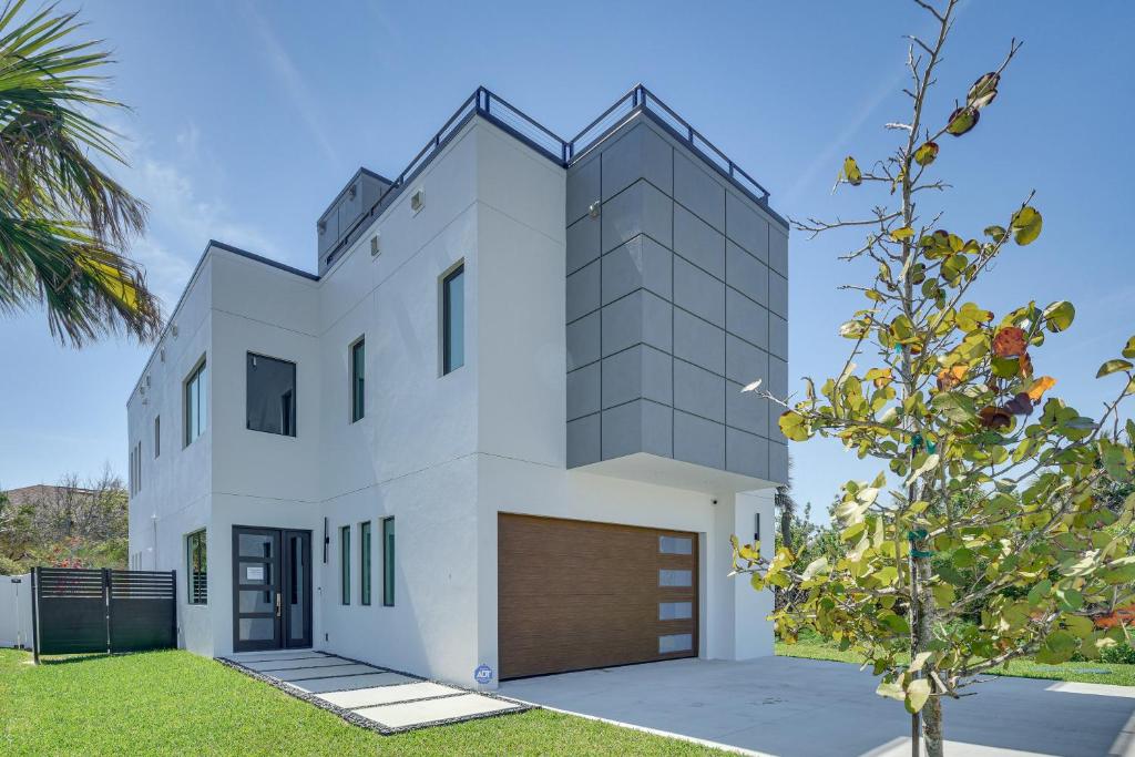 a white house with a brown garage at Walk to Shore Modern Stunner in Ormond Beach! in Ormond Beach
