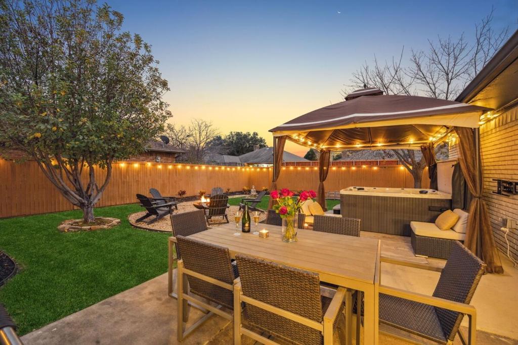 un patio con una mesa y una sombrilla en Zen Back Yard with Hot Tub, Firepit, Spa at Home, en Dallas