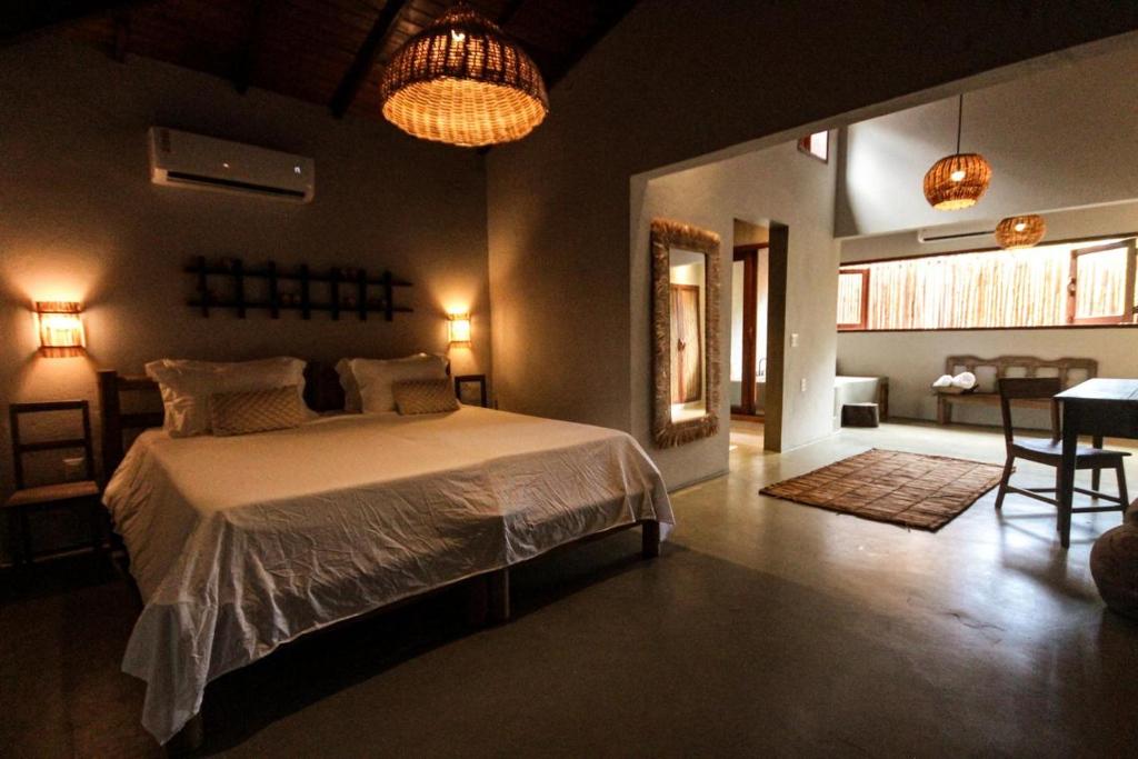 Un dormitorio con una cama y una sala de estar. en Caraíva Villas de Jardel - Casa Principal, en Caraíva