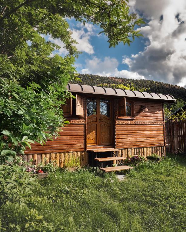 une cabane en bois avec une porte en bois dans l'herbe dans l'établissement Echolotte la roulotte, à Bernex