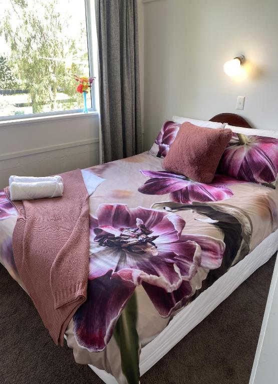 a bed with a purple flower blanket on it at Horseinaround in Cambridge