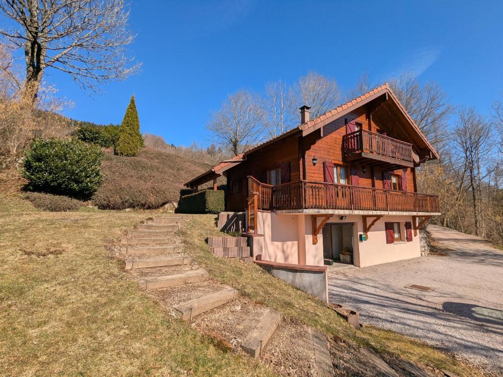 a wooden house with a balcony on a hill at Chalet confortable avec 4 chambres, cheminée, grand terrain, proche pistes et lac - FR-1-589-107 in Le Ménil