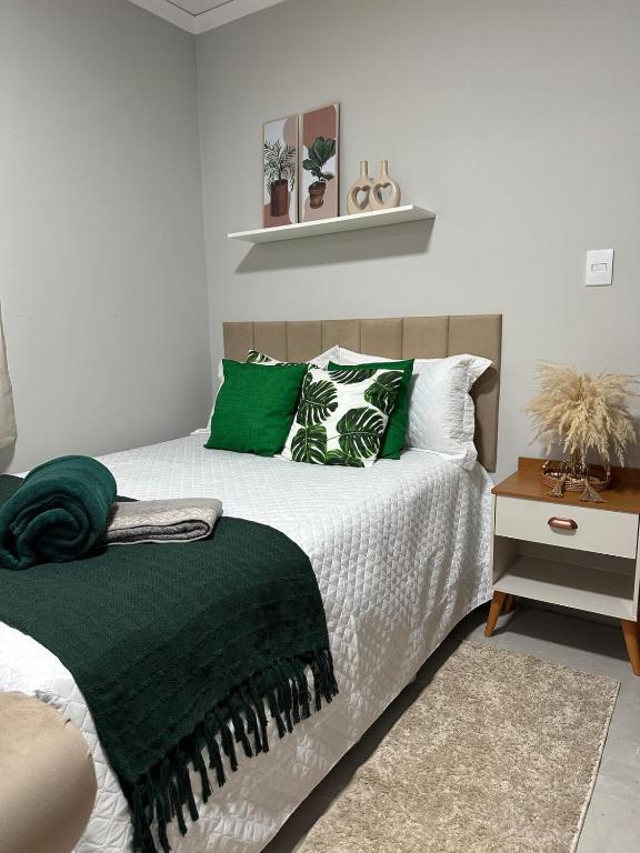 a bedroom with a bed with green and white pillows at Sinta-se em Casa in Cornélio Procópio