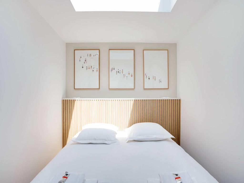 une chambre avec un lit avec trois tableaux au mur dans l'établissement Cosy & Modern Apartment - 1BR 4P - Montreuil, à Montreuil