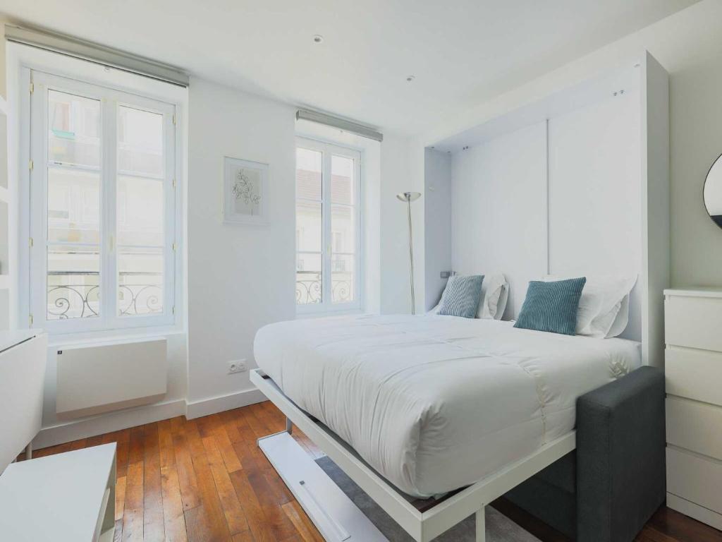une chambre blanche avec un grand lit et deux fenêtres dans l'établissement Charming apartment-1BR-3P-Ternes, à Paris