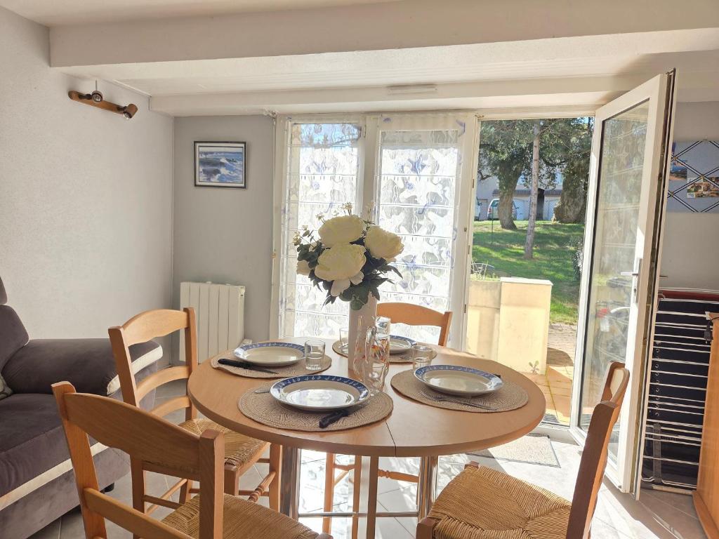 une table de salle à manger avec un vase de fleurs dessus dans l'établissement Confortable duplex avec terrasse, proche plage et commerces - St Brevin l'Océan - FR-1-364-43, à Saint-Brévin-les-Pins