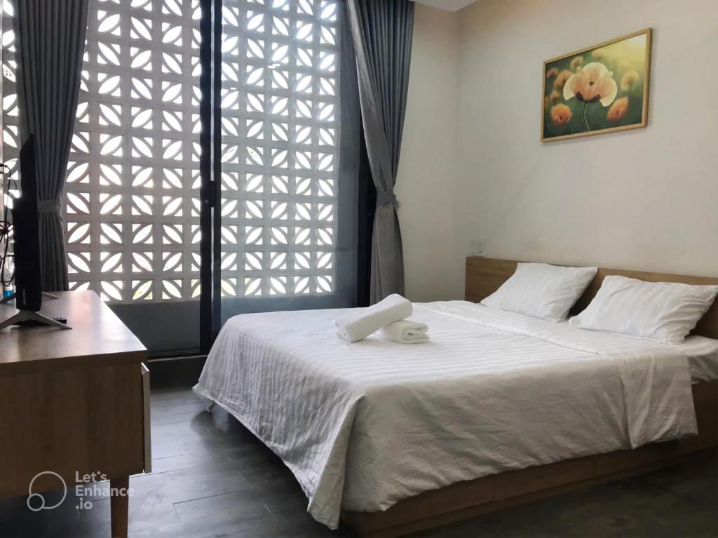 a bedroom with a white bed with a window at Gp Apartment View Beach in Da Nang