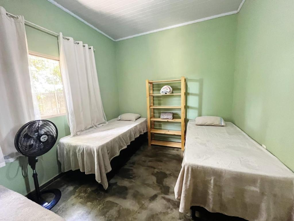 a green room with two beds and a window at Casa Bem te Vi - Cavalcante in Cavalcante