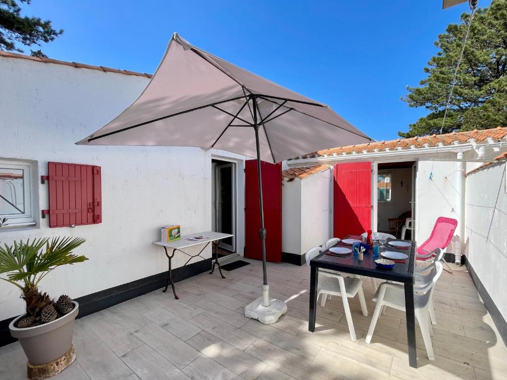 un patio avec une table et un parasol dans l'établissement Maison T3 tout confort proche mer, piscine chauffée, tennis - FR-1-231-301, à Bretignolles-sur-Mer