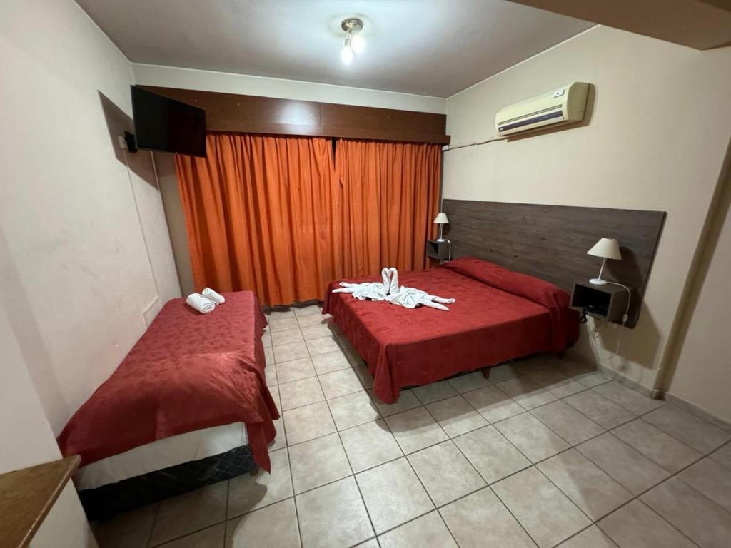a bedroom with two beds and a red curtain at Hotel El Torreon in Mendoza