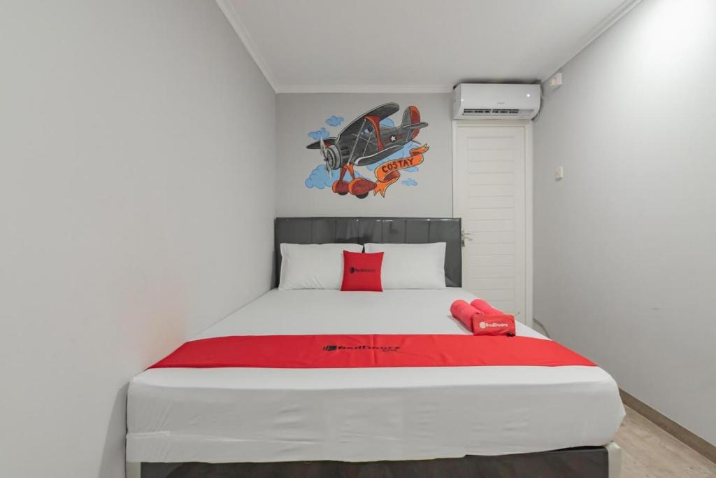 Un dormitorio con una cama grande con una manta roja. en RedDoorz Plus near Lembang Park & Zoo, en Bandung