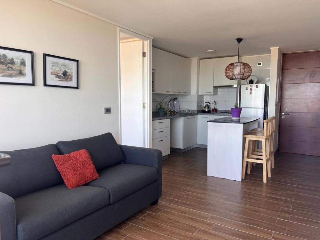 a living room with a couch and a kitchen at Depto equipado - WiFi rápido - 1 min de UCM - piscina rooftop in Talca