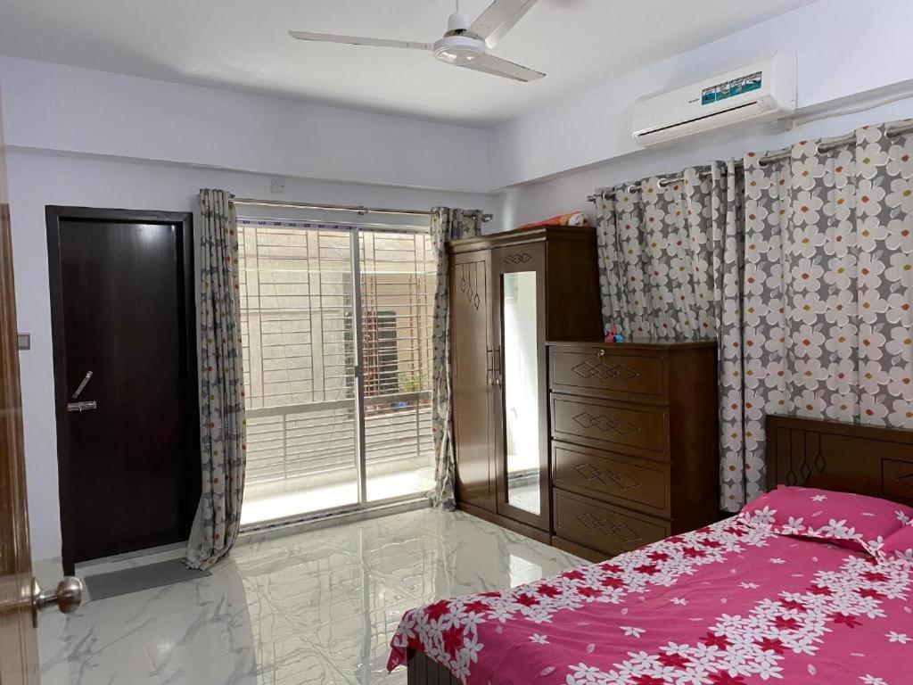 una camera da letto con un letto rosa e una finestra di Simply Apartement Rent a Dhaka
