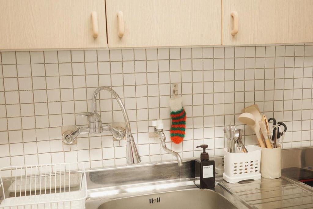a kitchen counter with a sink and a tiled wall at Cozy 3-4 person accommodation in Suwon