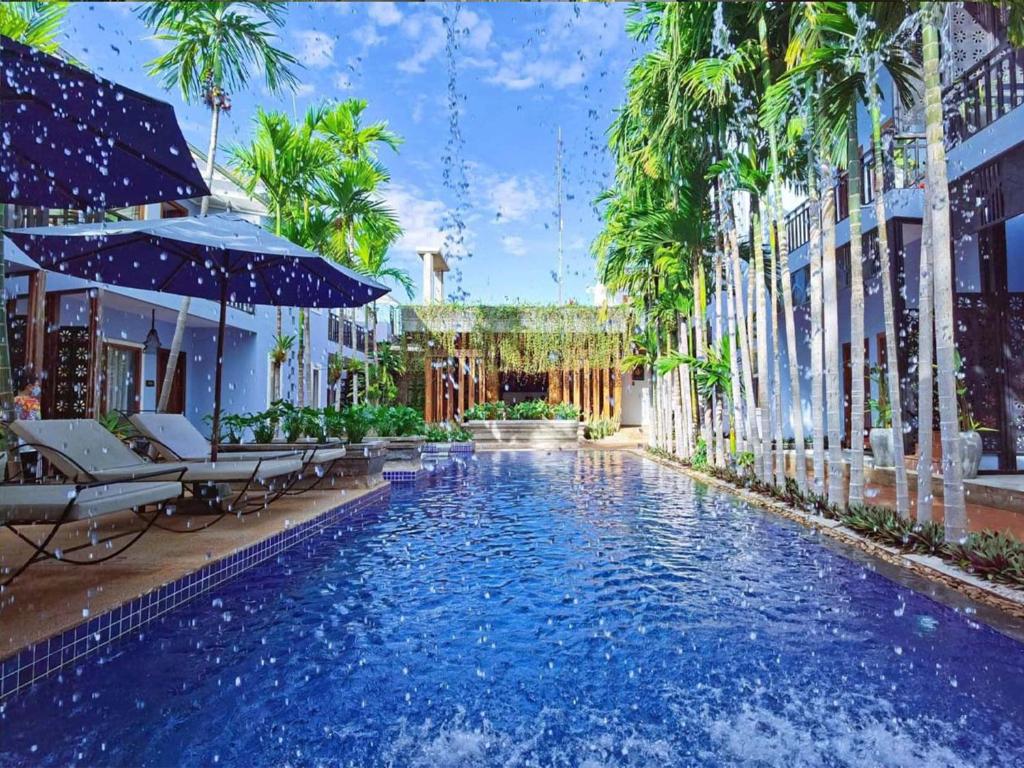 basen z krzesłami, parasolem i palmami w obiekcie Cheata Residence w Siem Reap