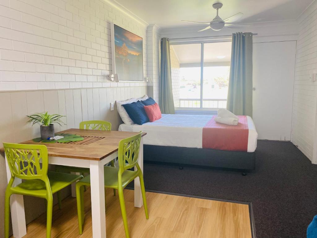 a bedroom with a bed and a table and chairs at Iluka Motel in Iluka