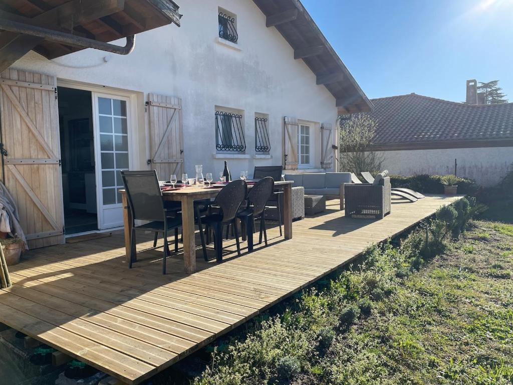 une terrasse en bois avec une table et des chaises dessus dans l'établissement Maison au calme entre lac et bourg, à Biscarrosse