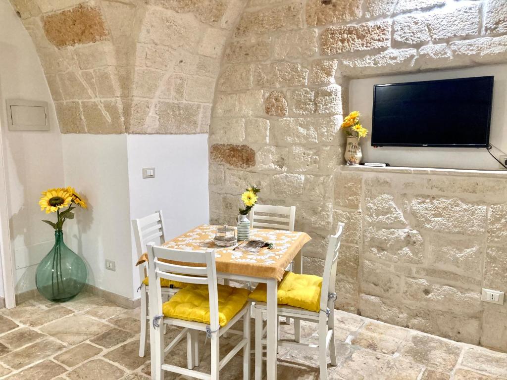 a dining room with a table and chairs and a tv at Antica Pietra in Polignano a Mare