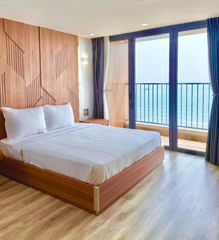 a bedroom with a large bed with a balcony at DA NANG BAY HOTEL in Danang