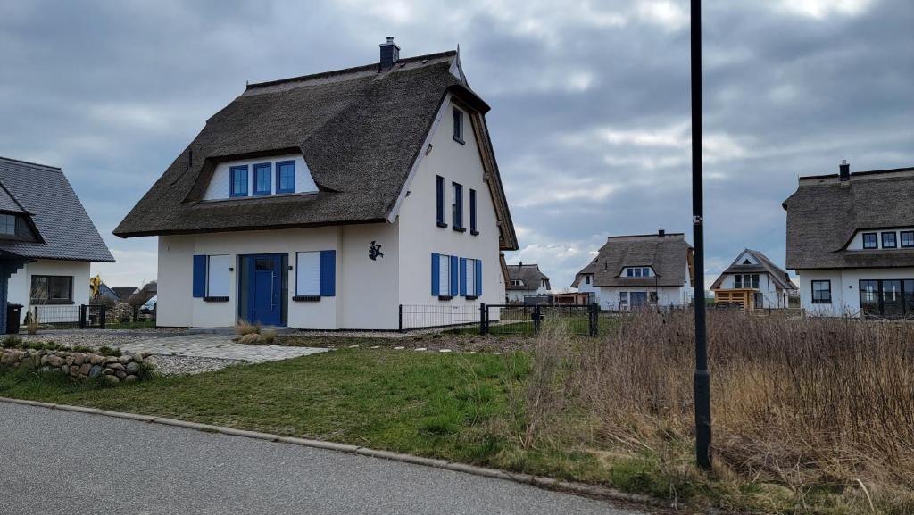 een wit huis met een grijs dak en blauwe ramen bij Ferienhaus Heimathafen Dranske in Dranske