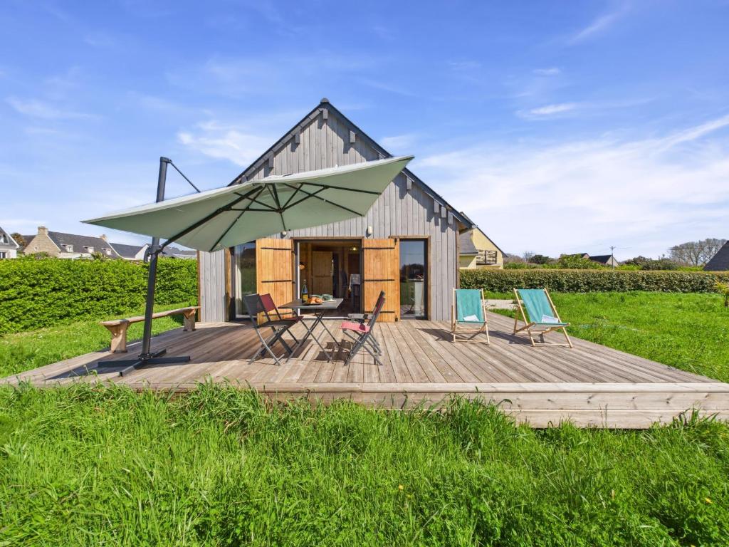 une maison avec un grand parasol vert sur une terrasse dans l'établissement 650m plage du Ster, chalet - terrasse pour 4, à Penmarcʼh