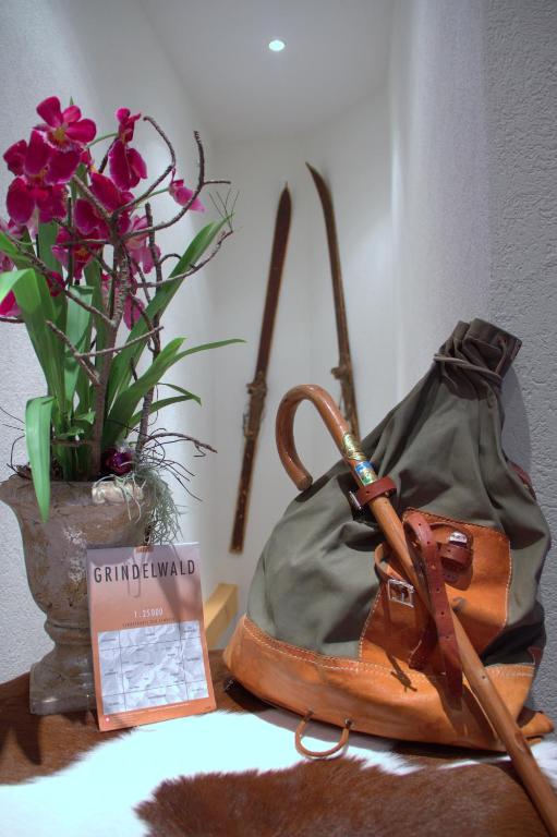 a purse and a vase with flowers on a table at Hotel Caprice - Grindelwald in Grindelwald