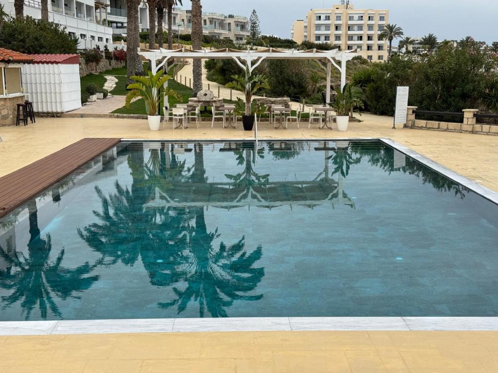 a large swimming pool with blue water at Vrachia Beach Hotel & Suites - Adults Only in Paphos