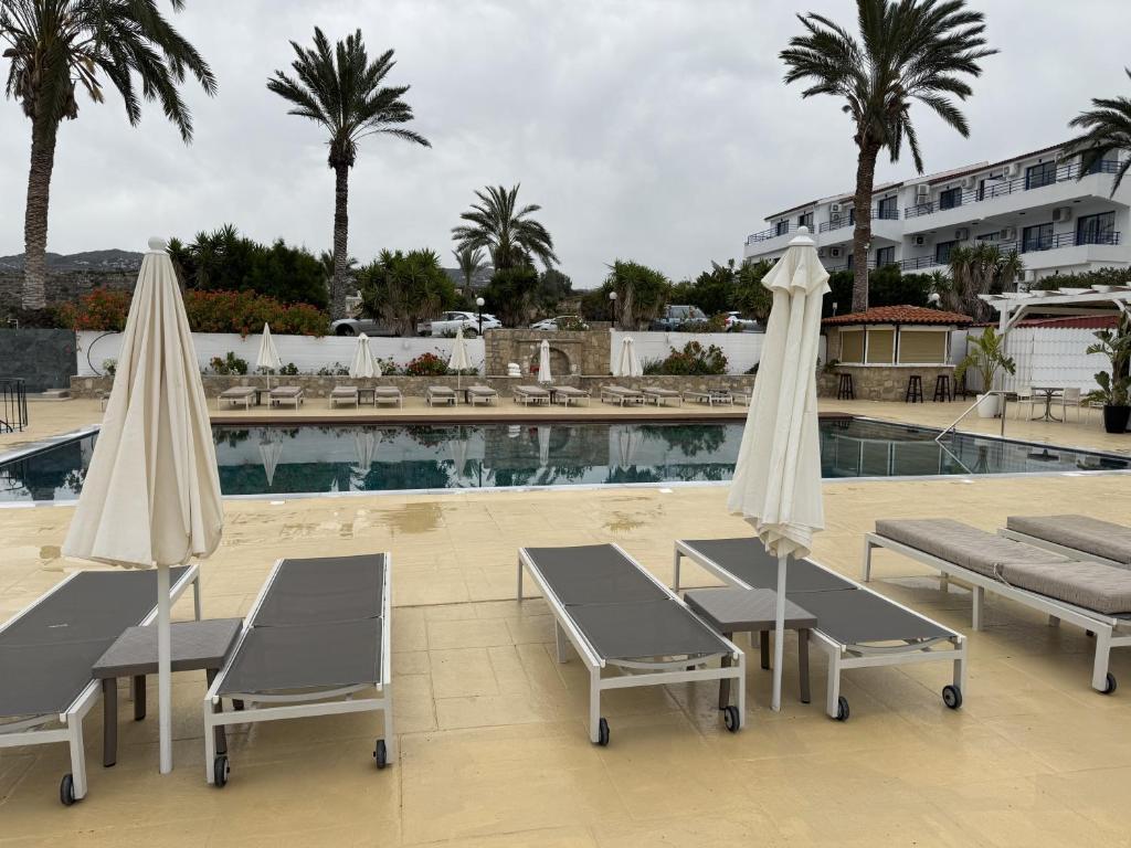 two chairs and umbrellas next to a swimming pool at Vrachia Beach Hotel & Suites - Adults Only in Paphos