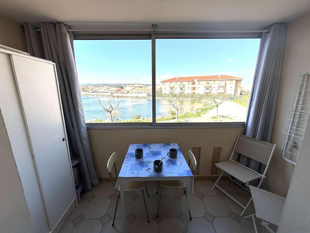 une table et des chaises dans une pièce avec une grande fenêtre dans l'établissement Appartement Studio-Cabine PORT-LA NOUVELLE PN290-074, à Port-la-Nouvelle