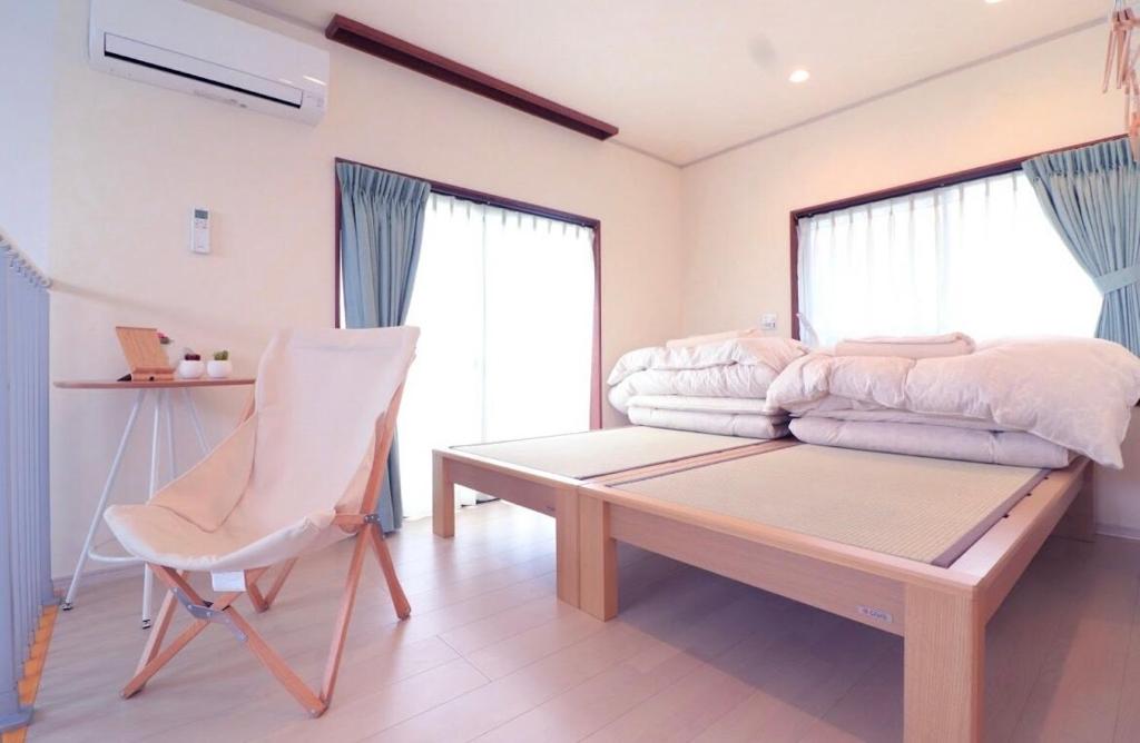 a bedroom with a bed and a chair and a table at 遊びの宿KONoさんち in Tateyama