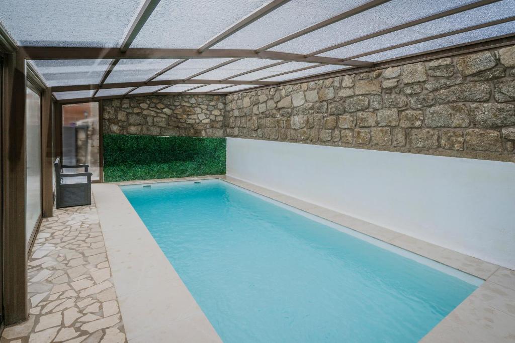 una piscina en un edificio con una pared de piedra en El Nogal de Marieta, en Peguerinos