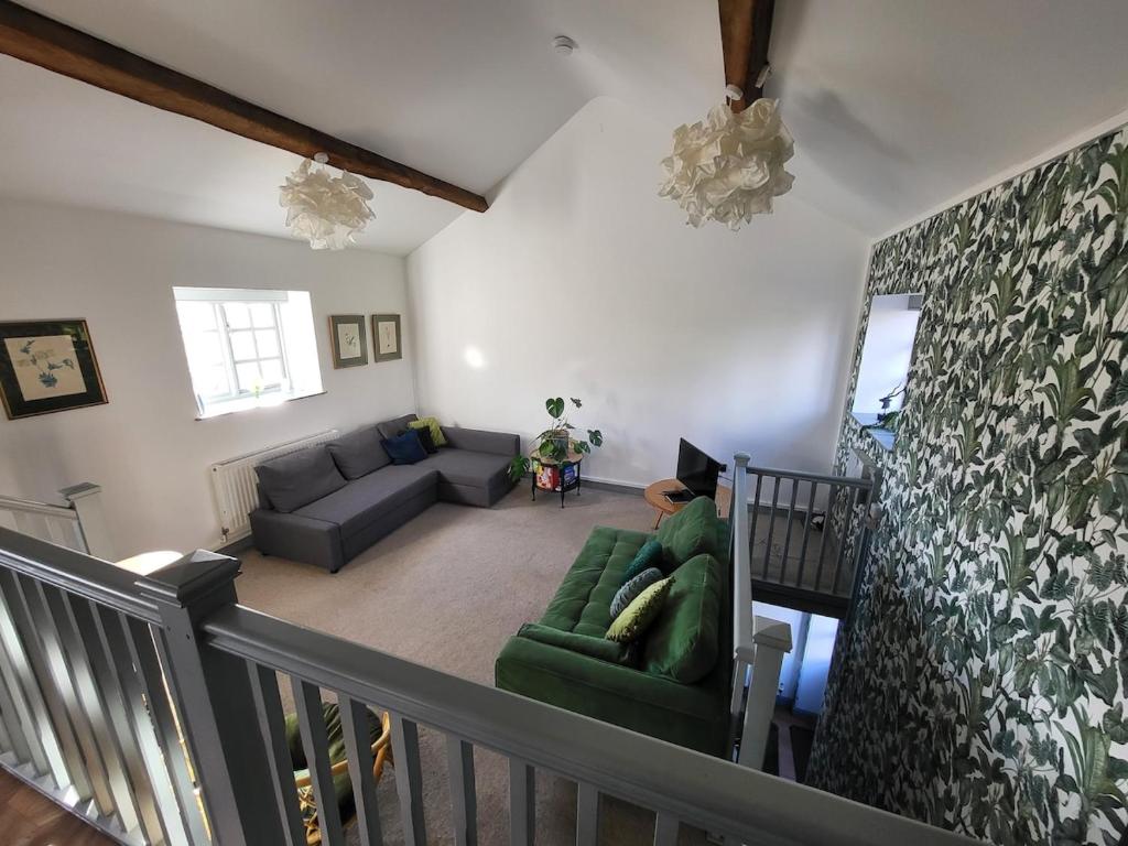 a living room with a green couch and a stair case at North Cottage in Berriew