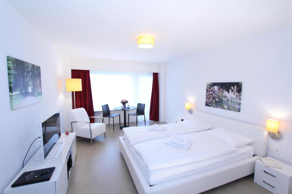 a white room with two beds and a table at CITY STAY - Forchstrasse in Zürich