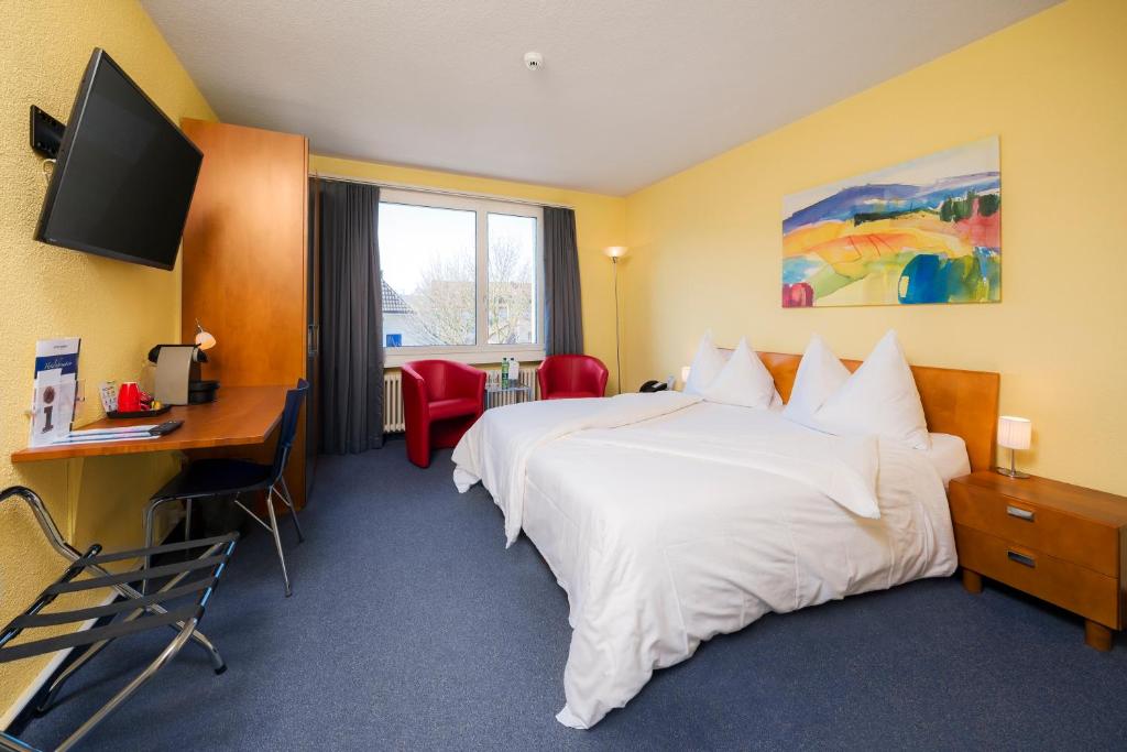 a hotel room with two beds and a desk and a television at Hotel Bären Suhr in Aarau
