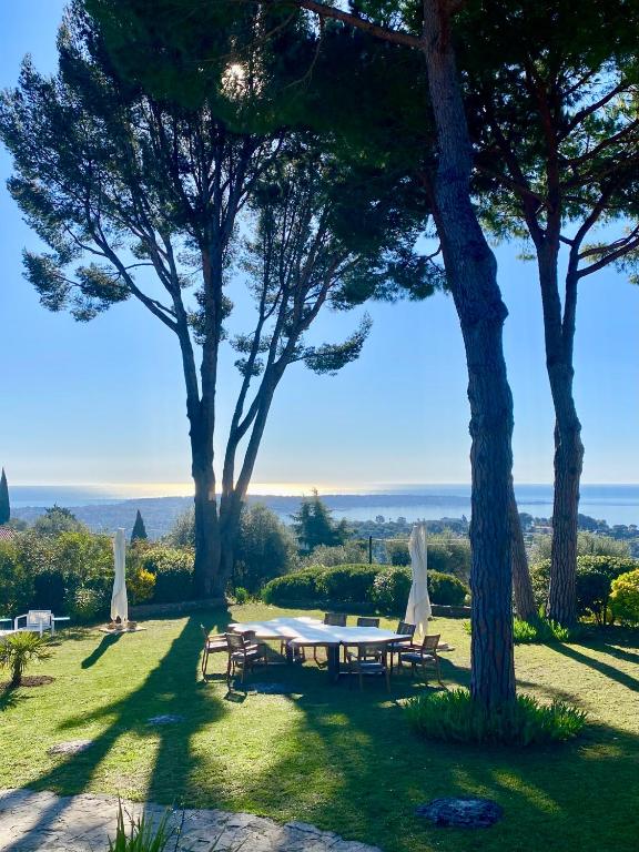 une table et des chaises dans un champ arboré dans l'établissement Domaine des Encourdoules, à Vallauris