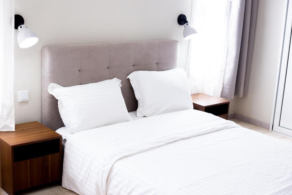 un dormitorio con una cama con sábanas y almohadas blancas en Tsiriry Guest House, en Antananarivo