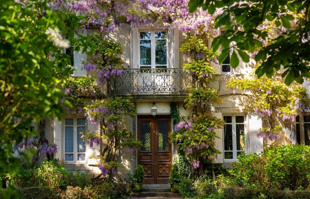 una casa con fiori viola sulla parte anteriore di Independent cottage with heated pool a Lempaut