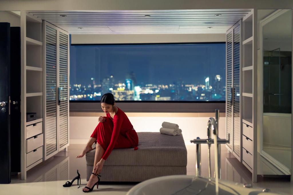 A bathroom features a freestanding tub beside a wide nighttime city view.