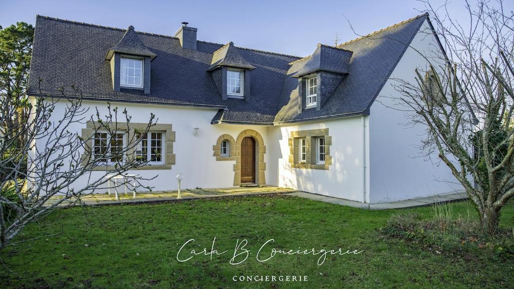 une maison blanche avec un toit noir et une cour dans l'établissement La VILLA DU CABELLOU, à Concarneau