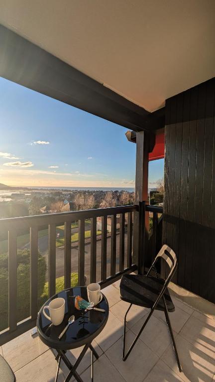 d'un balcon avec deux chaises et une table en verre. dans l'établissement Le Panoramique, F2- vue imprenable, wifi & parking, à Blonville-sur-Mer