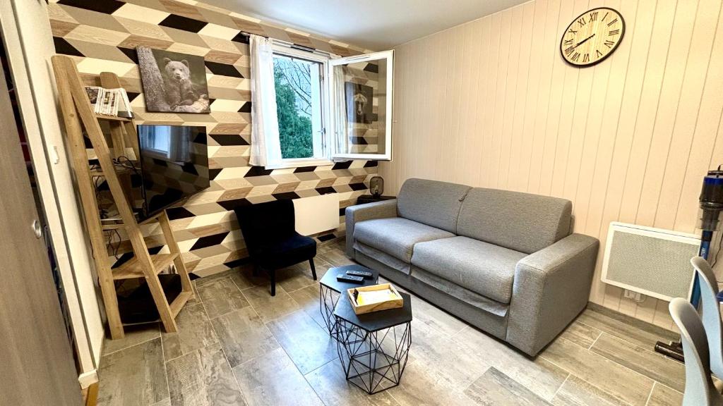 un salon avec un canapé et une horloge au mur dans l'établissement Chez Yoyo & Mag - T2 en centre ville - Wi-Fi - Parking, à Luchon