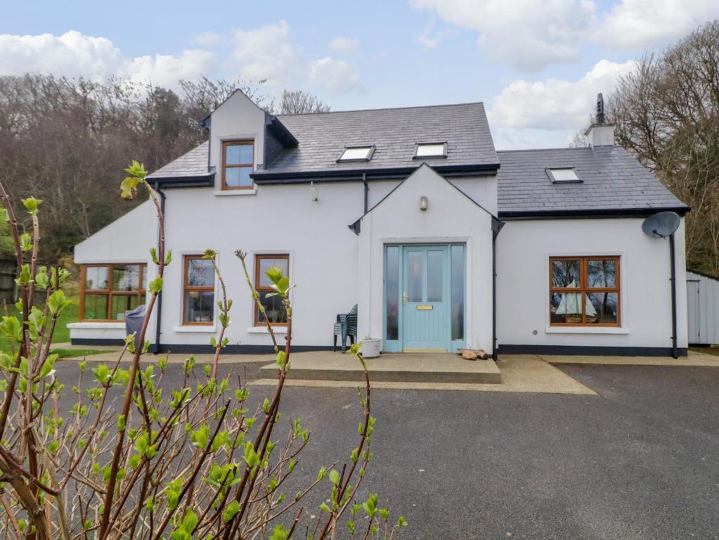 a white house with a blue door at Clondallon Cottage in Rathmullan
