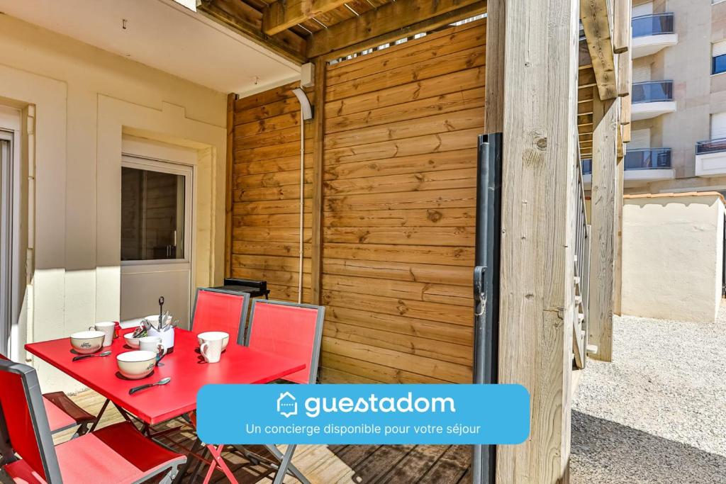 une table et des chaises rouges sur une terrasse avec un mur en bois dans l'établissement Le Remblai - 50m de la plage - Terrasse, à Saint-Jean-de-Monts