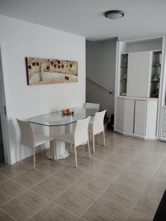 a dining room with a glass table and white chairs at Casa Roc de Sant Gaietà in Comarruga